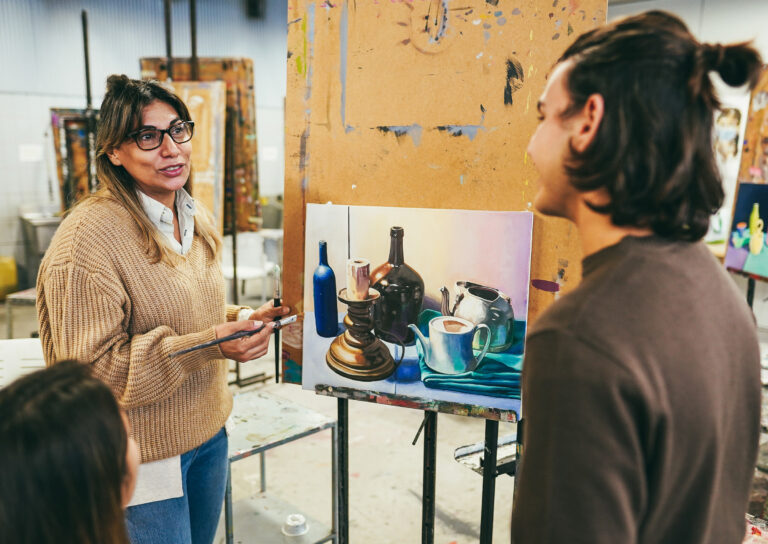 Mature teacher working with art students during painting class at school - Focus on teacher face