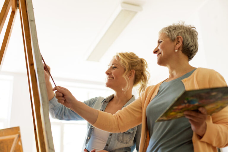 women with brushes painting at art school